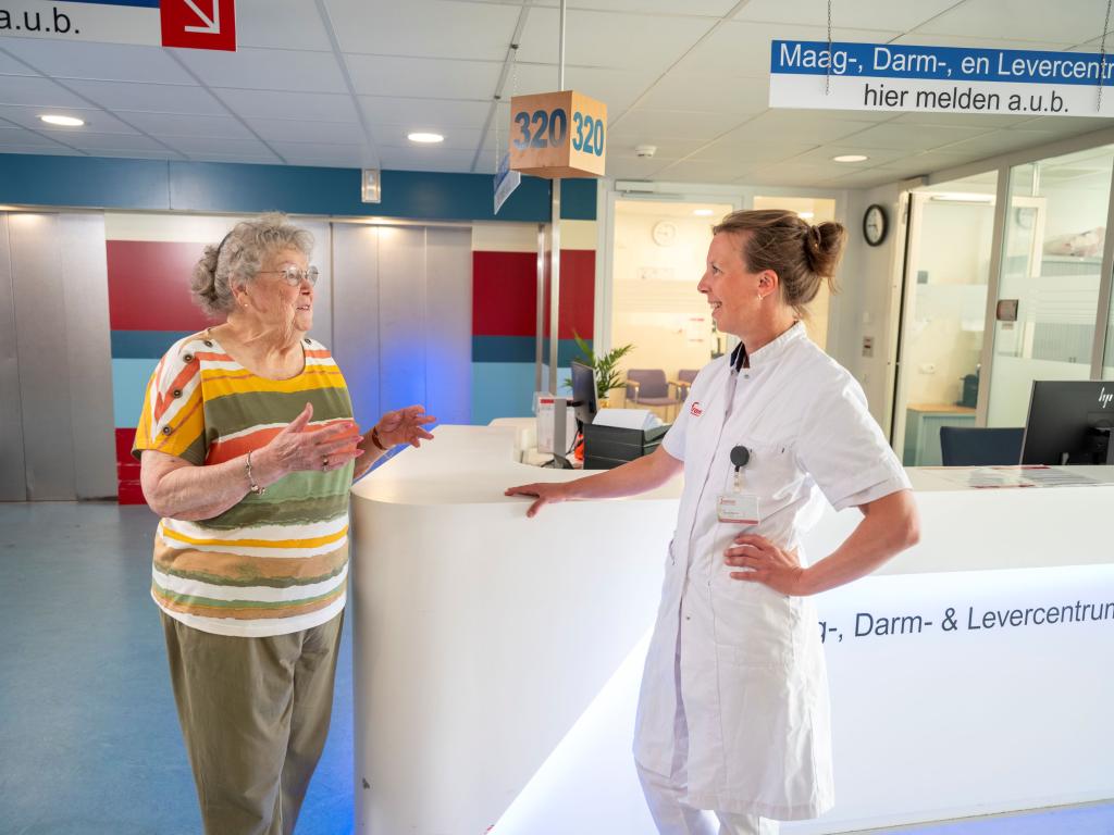 Dokter Leemreis spreekt met patiënt bij de balie