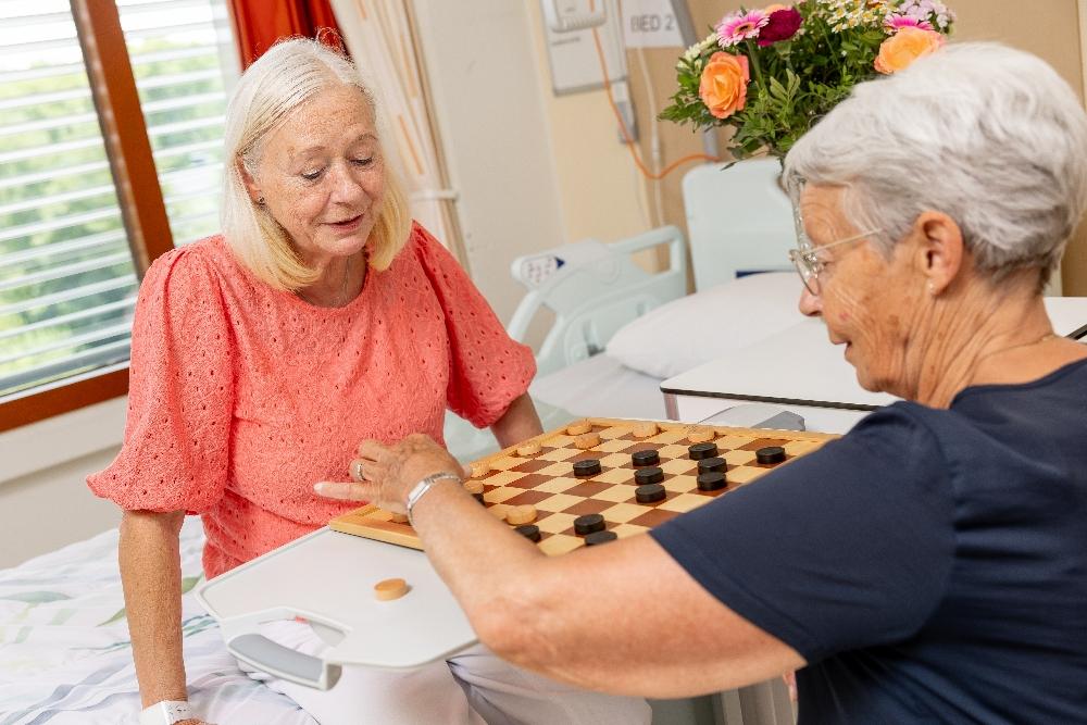 Mantelzorger en patiënt spelen een potje dammen