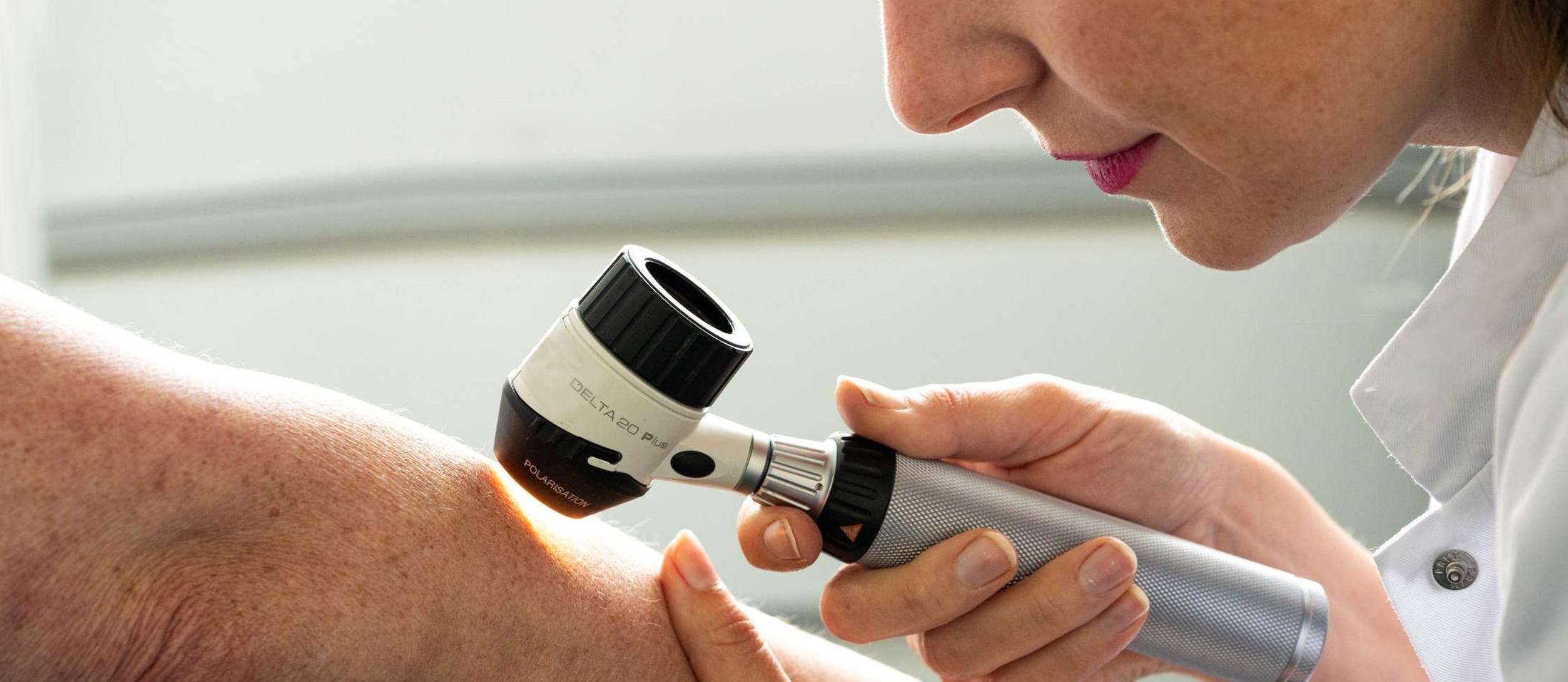 Dermatoloog bekijkt de huid van een patiënt